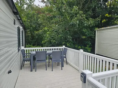 a wooden deck with a table and chairs on it at Mawgan Pads Trevella Crantock in Crantock