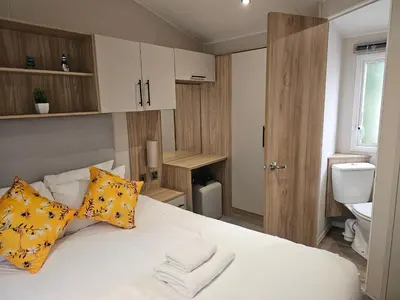 a bedroom with a white bed with yellow pillows at Mawgan Pads Trevella Crantock in Crantock