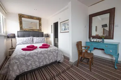 a bedroom with a bed with two red pillows on it at Cornerways Guest House in St Ives