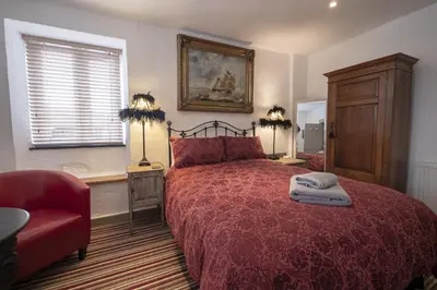 a bedroom with a red bed and a red chair at Cornerways Guest House in St Ives