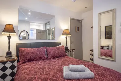 a bedroom with a red bed with a mirror at Cornerways Guest House in St Ives