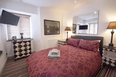 a bedroom with a bed with a red comforter and a mirror at Cornerways Guest House in St Ives