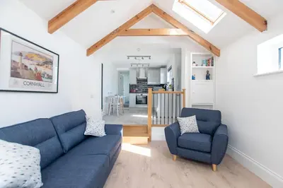 a living room with a blue couch and two chairs at Marcella's Retreat in St Ives