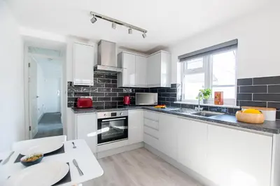 a white kitchen with white cabinets and a table at Marcella's Retreat in St Ives