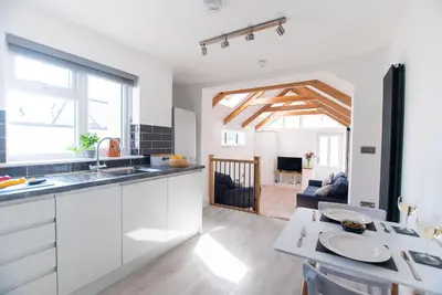a kitchen with white cabinets and a living room at Marcella's Retreat in St Ives