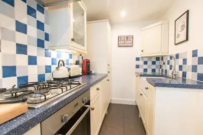 a kitchen with blue and white tiles on the wall at Stone's Throw in St Ives
