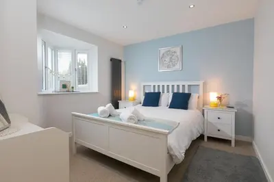 a bedroom with a white bed with blue pillows at Chi Lowen in Carbis Bay