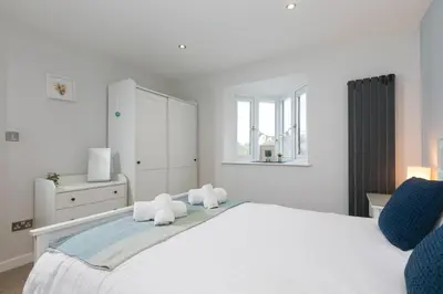 a white bedroom with a large bed and a window at Chi Lowen in Carbis Bay