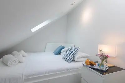 a white bed with pillows and a night stand at Chi Lowen in Carbis Bay