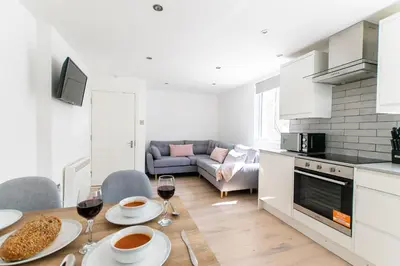 a kitchen and living room with a table with glasses of wine at Beached Az in St Ives
