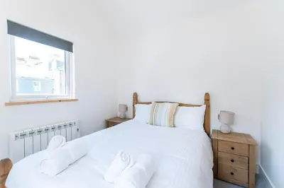 a bedroom with a bed with white sheets and a window at Beached Az in St Ives