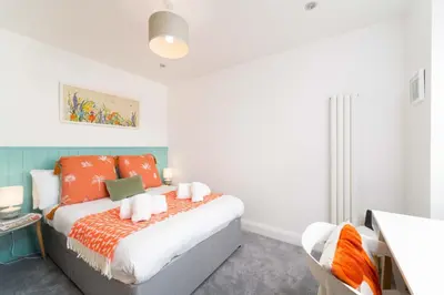 a bedroom with a bed with orange pillows at Mavericks in St Ives