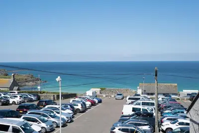 a parking lot with cars parked next to the ocean at Mavericks in St Ives
