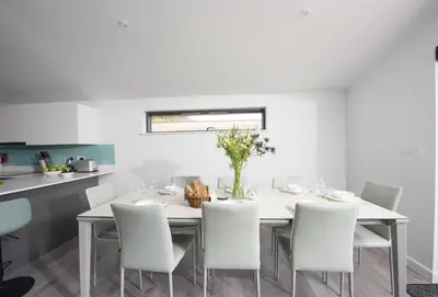 a white dining room with a table and chairs at The Shore in Mawgan Porth