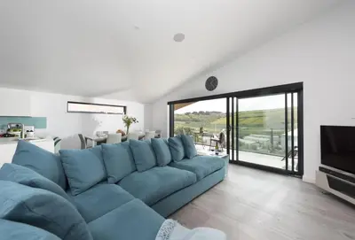 a living room with a blue couch and a television at The Shore in Mawgan Porth