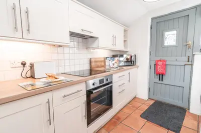 a kitchen with white cabinets and a blue door at Salty's Cottage in St. Agnes