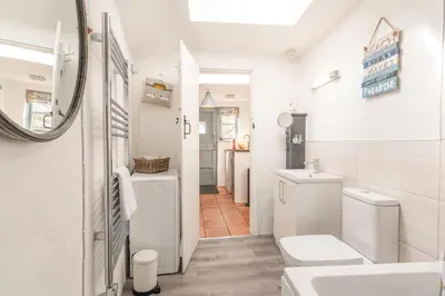 a white bathroom with a toilet and a sink at Salty's Cottage in St. Agnes