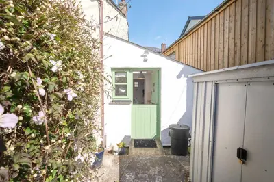 a white house with a green door and a bush at Salty's Cottage in St. Agnes