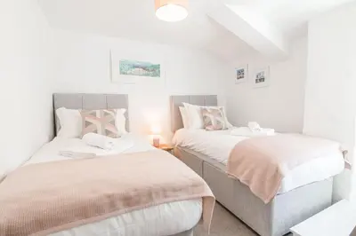 two beds in a small bedroom with white walls at Salty's Cottage in St. Agnes