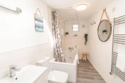 a white bathroom with a toilet and a sink at Salty's Cottage in St. Agnes