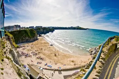 a beach with people on the sand and the ocean at Large 5 bed 3 bath house 300 meters from beach and restaurants in Newquay