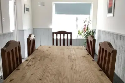 a long wooden table in a room with chairs at Large 5 bed 3 bath house 300 meters from beach and restaurants in Newquay