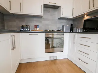 a kitchen with white cabinets and a stove top oven at 23 Tre Lowen in Newquay