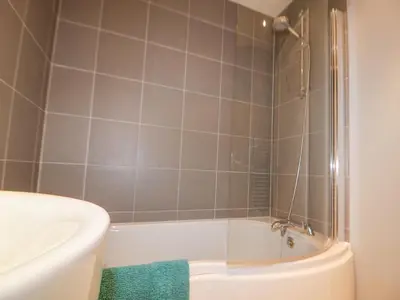 a bathroom with a bath tub and a sink at 23 Tre Lowen in Newquay