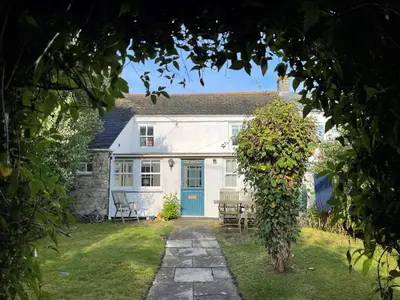 a white house with a blue door and chairs at Mapa Cottage in Mount Hawke