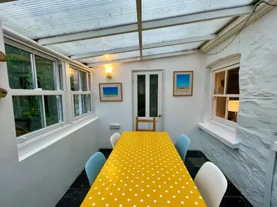 a yellow table and chairs in a room with windows at Mapa Cottage in Mount Hawke