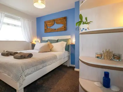 a bedroom with a bed with blue walls at Estuary View in Newquay
