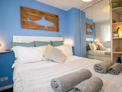 a bedroom with a white bed with a blue wall at Estuary View in Newquay
