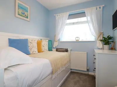 a bedroom with a bed with blue walls and a window at Estuary View in Newquay