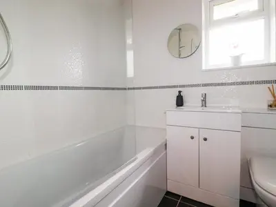 a white bathroom with a tub and a sink at Estuary View in Newquay