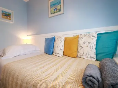 a bedroom with a bed with colorful pillows at Estuary View in Newquay