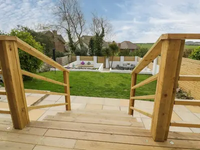 a wooden stairway leading to a patio with a yard at Estuary View in Newquay
