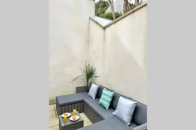 an apartment patio with a blue couch and pillows at Luna Beach - Luxury Carbis Bay Apartment + Parking in Carbis Bay