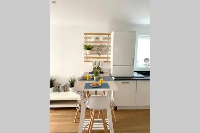 a kitchen with white cabinets and a table and chairs at Luna Beach - Luxury Carbis Bay Apartment + Parking in Carbis Bay