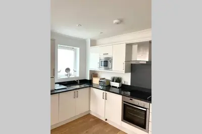 a kitchen with white cabinets and black counter tops at Luna Beach - Luxury Carbis Bay Apartment + Parking in Carbis Bay