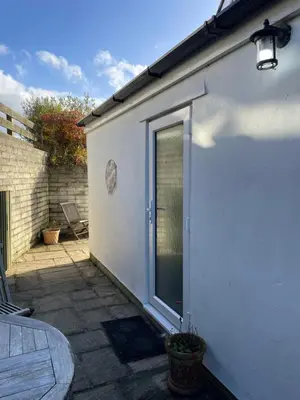 a white building with a door and a patio at Rose Cottage Bee Happy anex in Newquay