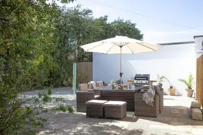 a patio with a table and an umbrella and chairs at Bridge Apartment - Free Parking & WiFi - Near Perranporth Beach in Perranporth
