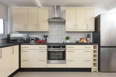 a kitchen with white cabinets and a stainless steel refrigerator at Bridge Apartment - Free Parking & WiFi - Near Perranporth Beach in Perranporth