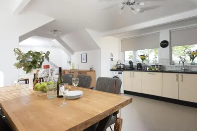 a kitchen and dining room with a wooden table at Bridge Apartment - Free Parking & WiFi - Near Perranporth Beach in Perranporth