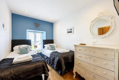 a bedroom with two beds and a dresser and a mirror at 8 Fernhill in Carbis Bay