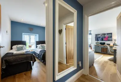 a bedroom with blue walls and a bed and a mirror at 8 Fernhill in Carbis Bay