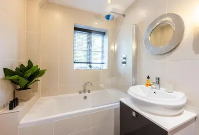a white bathroom with a sink and a tub and a mirror at 8 Fernhill in Carbis Bay