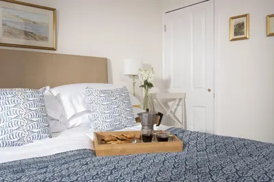 a bed with a tray with a vase of flowers on it at Greenfields Coach House - Balcony with stunning ocean view in Marazion
