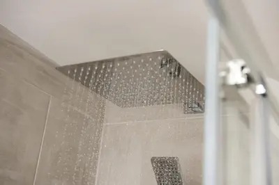 a bathroom with a shower with a tiled wall at Greenfields Coach House - Balcony with stunning ocean view in Marazion