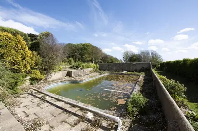 a pool of water in a field with trees at Greenfields Coach House - Balcony with stunning ocean view in Marazion
