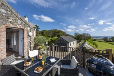 a view from the balcony of the cottage with a table and chairs at Greenfields Coach House - Balcony with stunning ocean view in Marazion